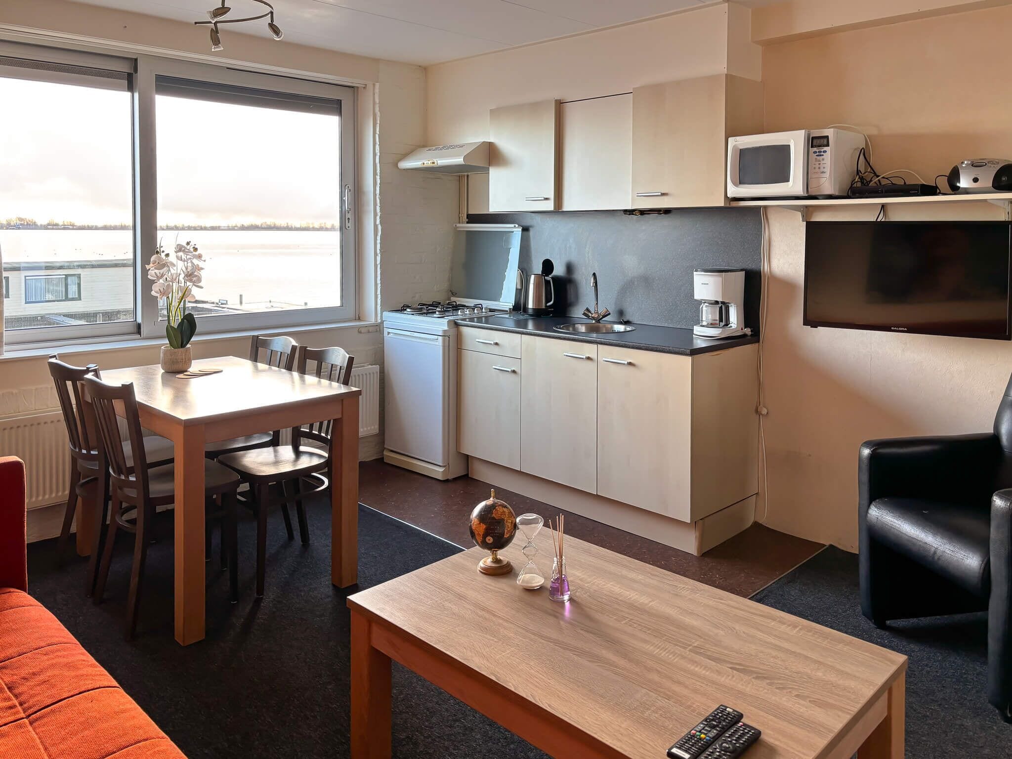 A compact kitchen with a dining area, a coffee machine, and a TV.