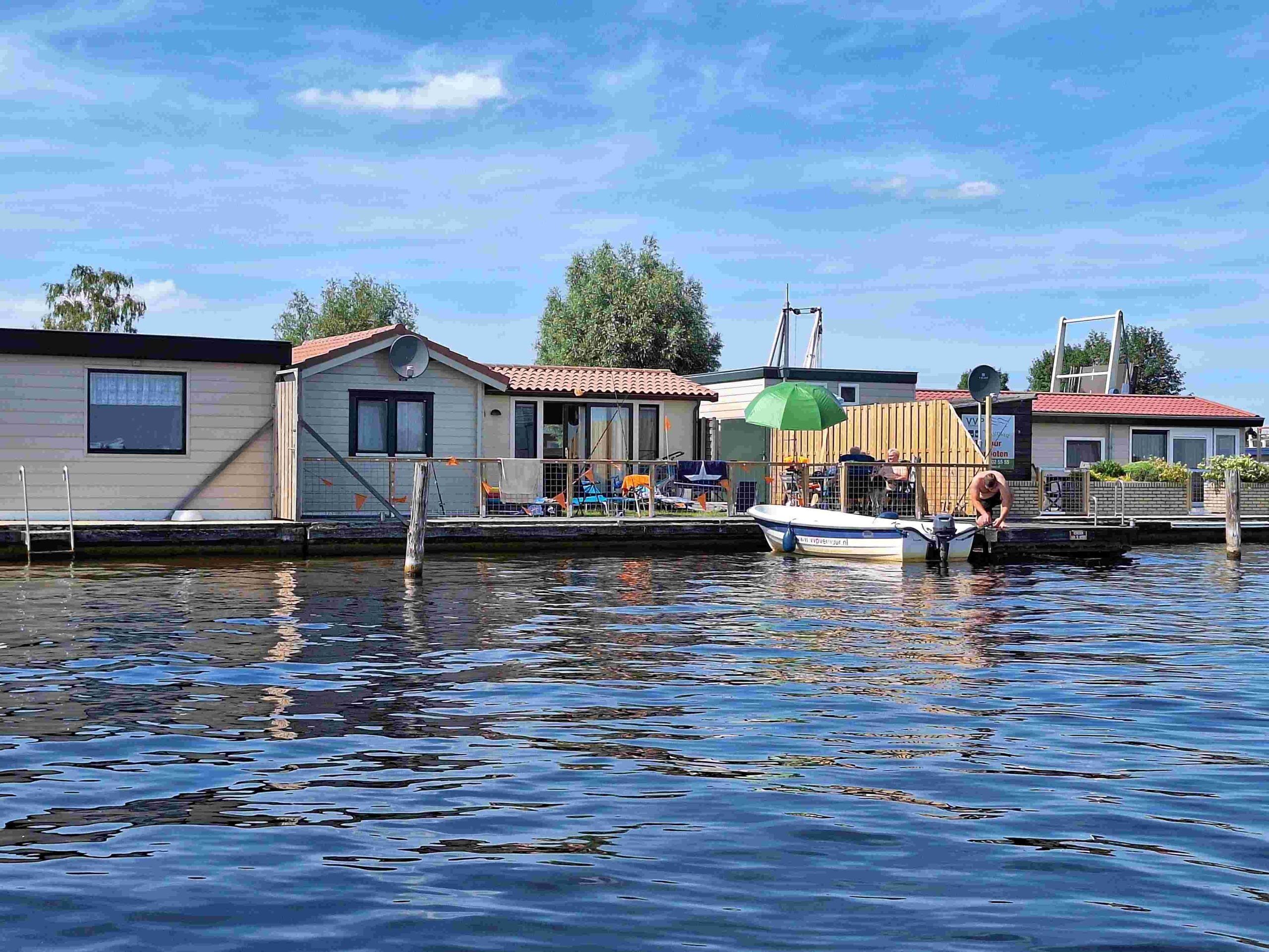 A waterfront property with a dock, a small boat, and a house with a satellite dish.