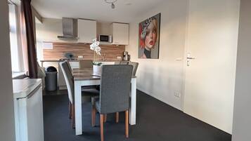 A modern kitchen with a dining area, white cabinets, a microwave, and a decorative painting.