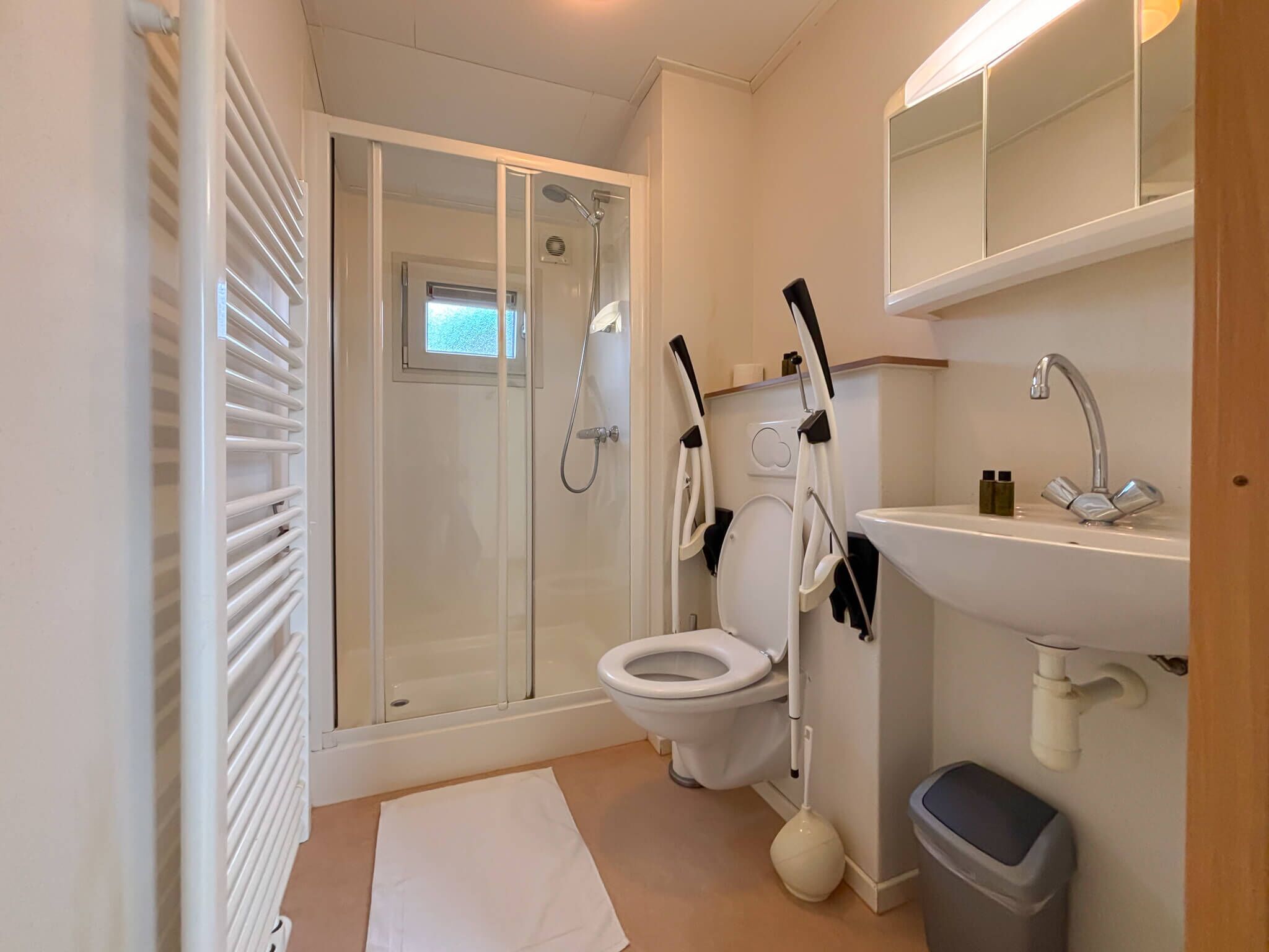 Een moderne badkamer met een douchecabine van glas, een toilet, een wastafel en een spiegel.