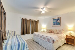 Ein Hotelzimmer mit Bett, Nachttisch mit Lampe, Deckenventilator und einem Bild an der Wand.