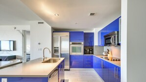A modern kitchen with blue cabinets, stainless steel appliances, and a large island with a sink. - Walk to Bars & Eats! Luxe Ft Lauderdale Condo (Fort Lauderdale)