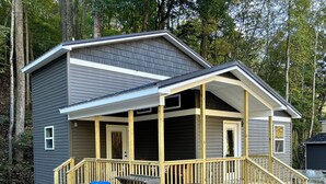 A two-story cabin with a covered porch, a grill, and a trash can. - A & W Goat Villa at Billy Goat Mountain Village (Williamson)
