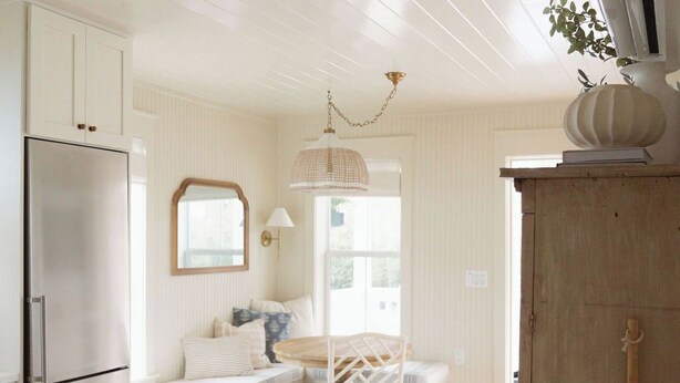 A kitchen with a built-in refrigerator, a wooden dining table with chairs, and a hanging light fixture.