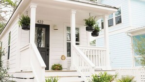 A white house with a black door, number 422, and a porch with hanging planters.