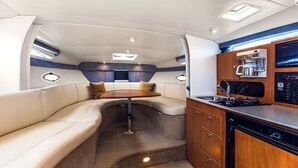 A compact, well-lit interior with a seating area, a small table, and a kitchenette. - A romantic night for couples in the yacht in Marina del Rey, Los Angeles (Marina del Rey)