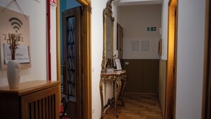 A hallway with a wooden floor, a mirror, a small table with a sign, and a door with a blue frame.