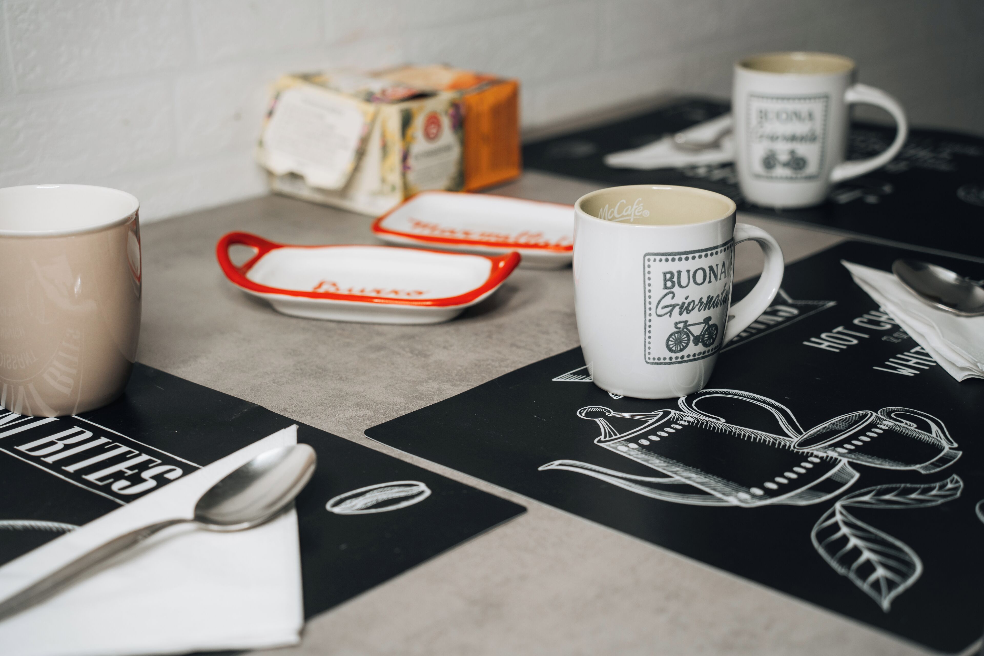 Una mesa con tazas de café, una cuchara y una servilleta.