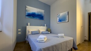 A bedroom with a bed, pillows, a bedside table, and two wall-mounted paintings.