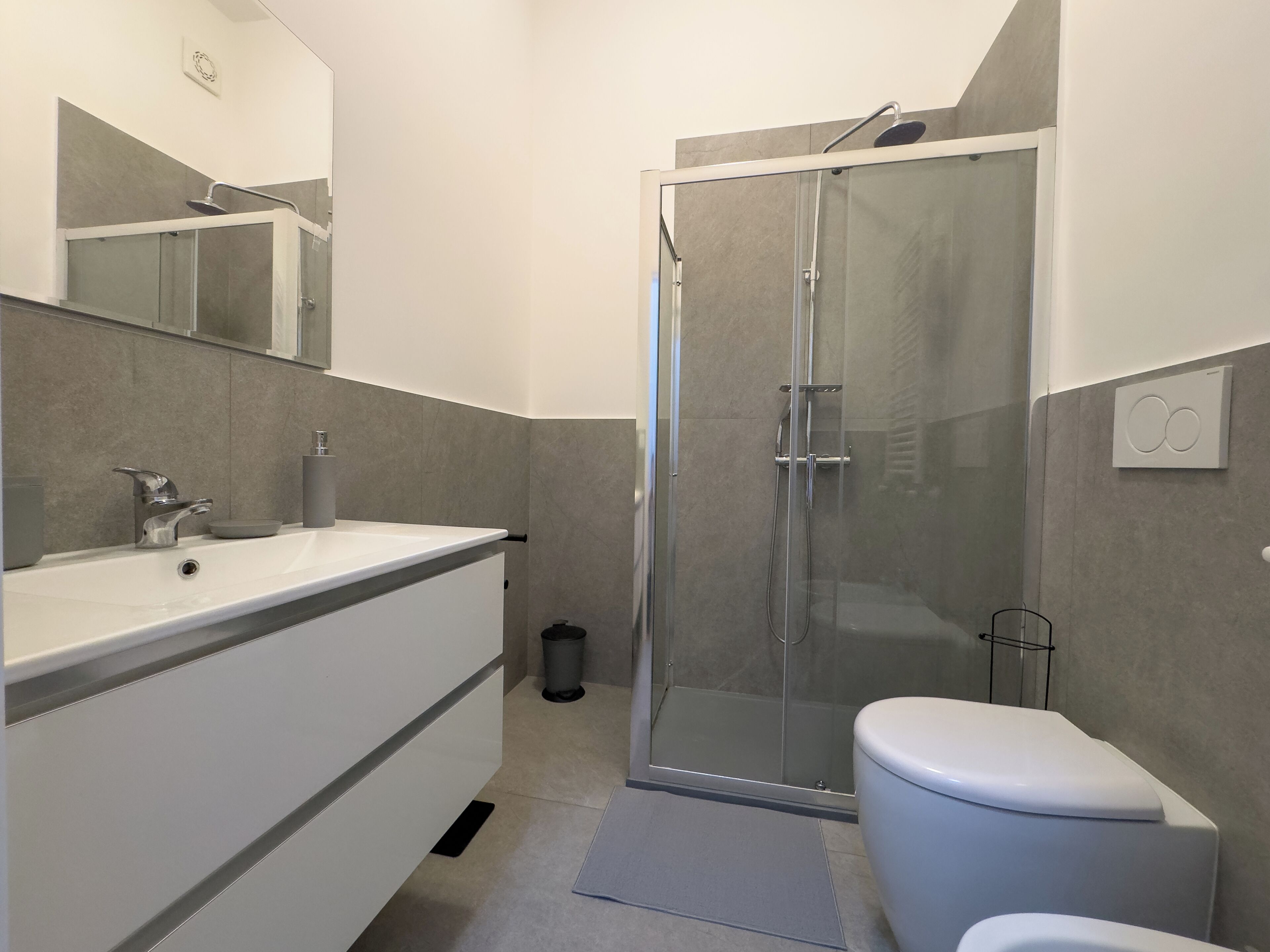 A modern bathroom with a glass-enclosed shower, a white sink, and a toilet.