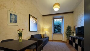 A modern living room with a dining table, sofa, and TV stand.