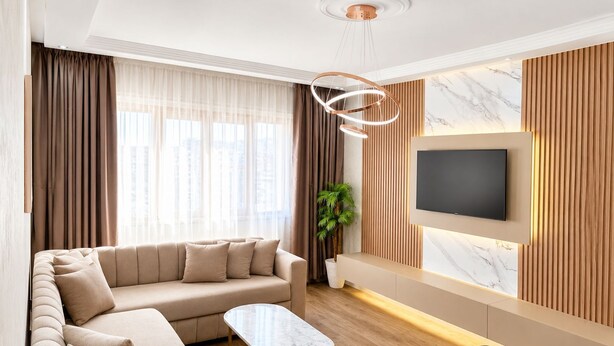 A modern living room with a sofa, a coffee table, and a TV mounted on the wall. - Tangier Center 3BR - Balcony, AC, Netflix & Wi-Fi (Tangier)