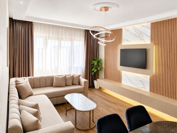 A modern living room with a sofa, a coffee table, and a TV mounted on the wall.