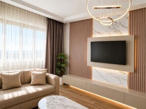 A modern living room with a sofa, a TV mounted on the wall, a marble coffee table, and a potted plant.