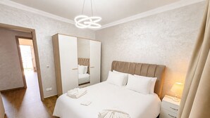 A hotel room with a large bed, a wardrobe, a bedside table with a lamp, and a mirror. - Tangier Center 3BR - Balcony, AC, Netflix & Wi-Fi (Tangier)