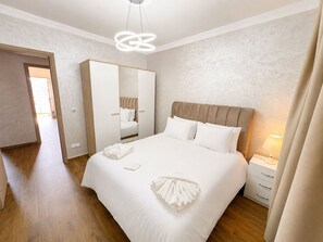 A hotel room with a large bed, a wardrobe, a bedside table with a lamp, and a mirror.