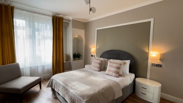 A bedroom with a bed, bedside tables, a chair, and a window with curtains.