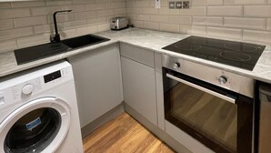 A compact kitchen with a built-in washing machine, a stove, and a microwave.