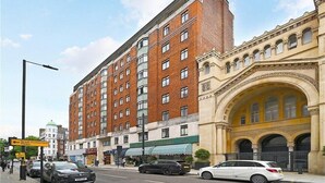 A multi-story building with a brick facade and a classical archway entrance.