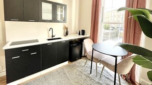 A compact kitchen with black cabinets, a white countertop, and a small dining area with a table and chairs.