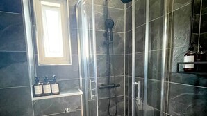 A modern bathroom with a glass-enclosed shower, a toilet, and a sink.