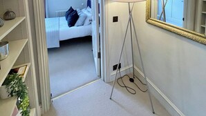A bedroom with a bed, bedside lamp, and a large mirror on the wall. - 2 bed Mews 2 minutes from Earls Court station (Greater London)