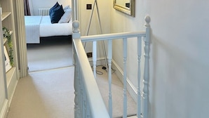 A staircase leading to a bedroom with a bed, a lamp, and a mirror. - 2 bed Mews 2 minutes from Earls Court station (Greater London)