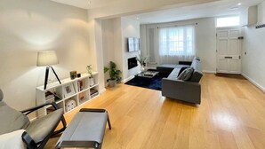 A modern living room with a grey sofa, a coffee table, and a bookshelf. - 2 bed Mews 2 minutes from Earls Court station (Greater London)