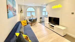 A modern living room with a sofa, TV, and dining area. - Cozy 1 bedroom flat near Tower Bridge (Greater London)