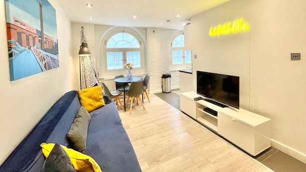 A modern living room with a sofa, TV, and dining area. - Cozy 1 bedroom flat near Tower Bridge (Greater London)
