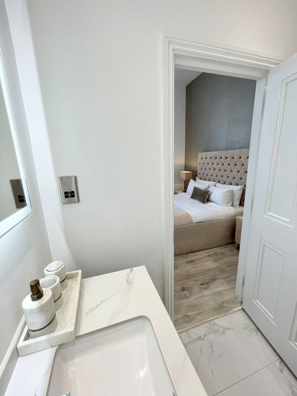 A modern bathroom with a large mirror, a marble countertop, and a built-in sink.