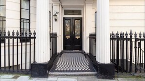 A building entrance with a black double door, a checkered floor, and a white facade. - Classy 2 bed apartment with high ceilings (Greater London)