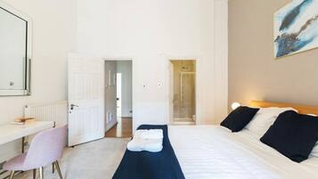 Een hotelkamer met een bed, een bureau, een stoel en een douche.
