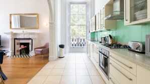 A spacious kitchen with a large window, a fireplace, and a view of the outside. - Classy 2 bed apartment with high ceilings (Greater London)