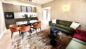 A modern living room with a green sofa, a coffee table, and a dining area with a glass table and chairs. - Lux Top floor 3 Bed Flat near Marble Arch (Greater London)
