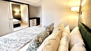 A bedroom with a bed, a nightstand, a dresser, and a sliding door leading to another room. - Lux Top floor 3 Bed Flat near Marble Arch (Greater London)