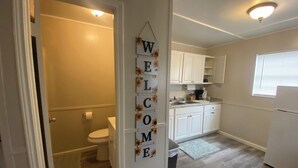 Een interieur met een badkamer, keuken en een welkomstbord.