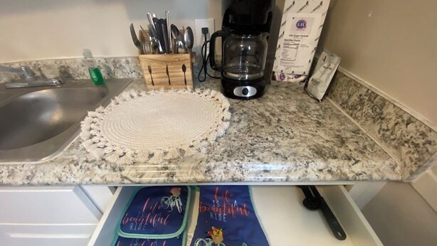 Een keuken met een granieten aanrecht, een koffiezetapparaat en een set messen in een houten blok.