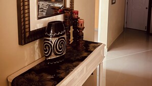 Un couloir avec un miroir, un vase décoratif et une porte.