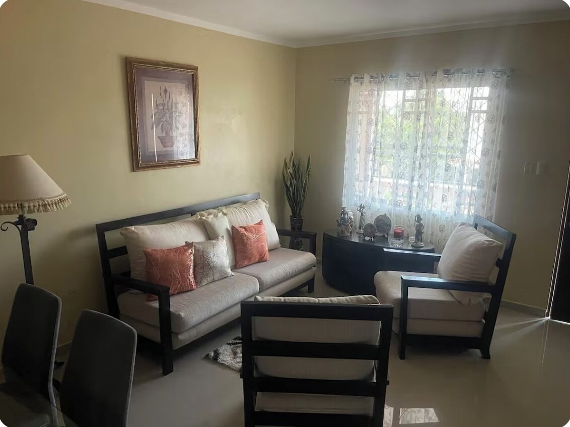 Una sala de estar con sofá, sillas, una mesa de centro y una lámpara.