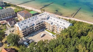 A multi-story hotel with a rooftop terrace, adjacent to a beach with clear waters and a pier. - Apartment With sea View, Ustronie Morskie (Ustronie Morskie)