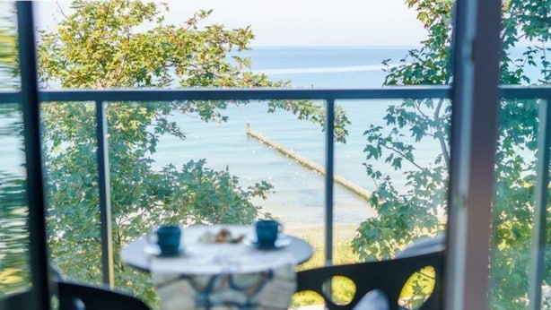 A balcony with a table and chairs, overlooking a body of water and trees. - Apartment With sea View, Ustronie Morskie (Ustronie Morskie)