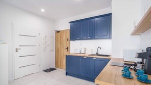 A modern kitchen with blue cabinets, a wooden countertop, and a coffee machine. - Apartment With sea View, Ustronie Morskie (Ustronie Morskie)