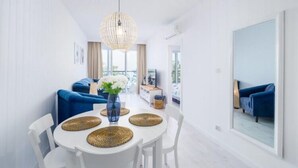 A modern dining area with a round table, white chairs, and woven placemats. - Apartment With sea View, Ustronie Morskie (Ustronie Morskie)