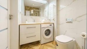 A compact bathroom with a washing machine, a toilet, and a mirror above the sink. - Apartment With sea View, Ustronie Morskie (Ustronie Morskie)