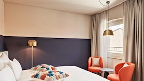 A hotel room with a large bed, two chairs, a small table, a lamp, and a window with curtains. - Schone Wohnung mit Aufzug (Trieste)