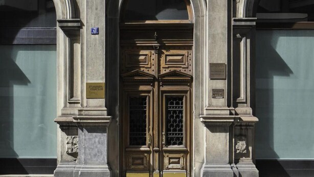 A building facade with a central arched entrance, flanked by two symmetrical windows with stone frames. - Schone Wohnung mit Aufzug (Trieste)