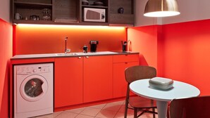 A compact kitchen with a washing machine, a microwave, and a coffee maker. - Schone Wohnung mit Aufzug (Trieste)