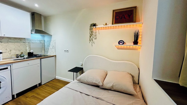 A compact bedroom with a bed, bedside table, and a small kitchen area with a stove and sink. - Mini - Small but cozy! (Brignoles)