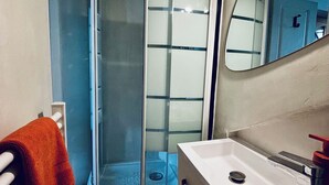 A bathroom with a glass-enclosed shower, a white sink, and a mirror. - Mini - Small but cozy! (Brignoles)